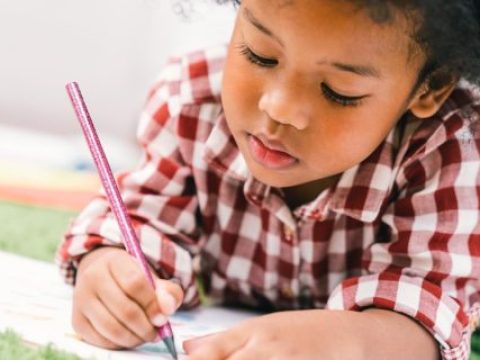 Cute young African American kid girl drawing or painting with colored pencil. Kindergarten children education, or preschool child study at home concept